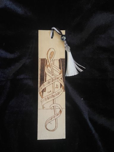 Wooden bookmark with intricate engraved design and a decorative tassel.