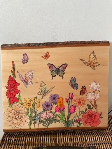 A wooden surface adorned with painted butterflies and various colourful flowers.